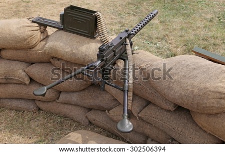 big machine gun with bullets over the sandbags in the trench