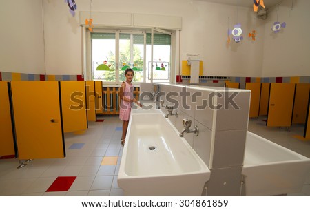 smiling girl washing her hands in the sink in the bathroom of the school
