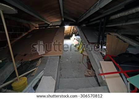 Junk and old furniture in large attic under the roof of the school