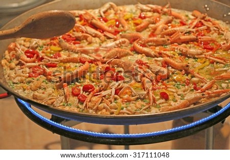 Spanish paella with prawns and rice cooked on a pot in the restaurant
