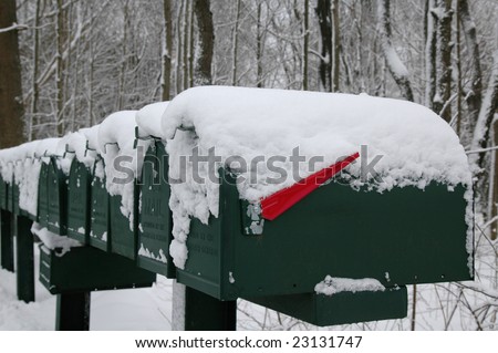 A row of green mailboxes draped with a layer of freshly fallen snow