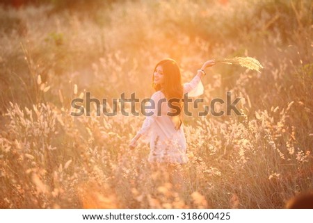 Beautiful woman in field of meadow holding flower in flare light