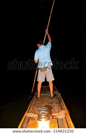 PAI, THAILAND - MARCH 10 : A man standing on a bamboo raft and rowing inside Lod cave on March 10, 2012 in Maehongson Province, Thailand