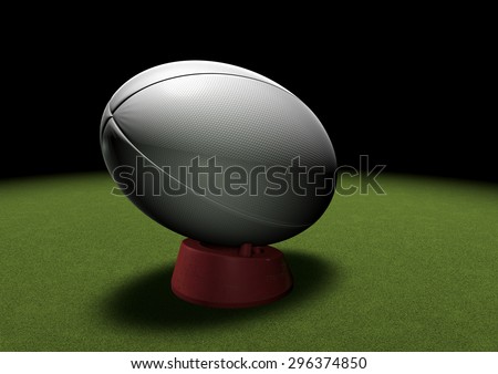 Rugby ball on a kicking tee waiting to be kicked. Spotlight on grass.