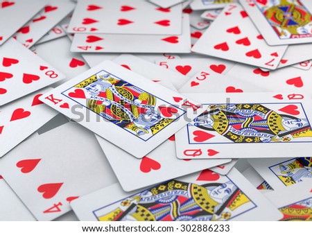 Pile of cards heart suite spread out and lying on table with depth of field. King and Queen of hearts are focal points. Background texture or image.