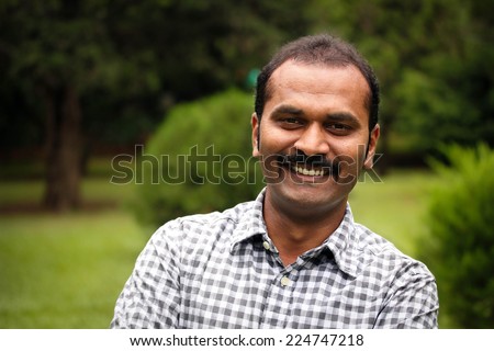 happy, smiling indian male or latin american man. The person can also represent a south asian or a mexican male businessman, executive or employee in positive relaxed mood