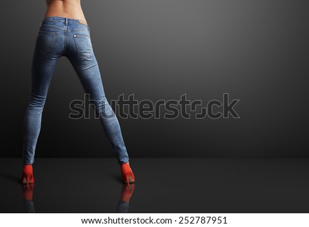 perfect shaped woman wearing skinny jeans in a dark room