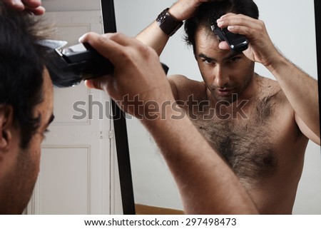 Man having a haircut by himself. watching in a mirror