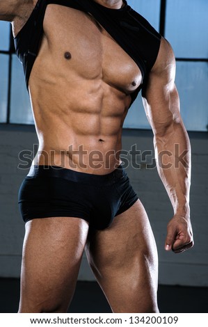 Muscular male torso of fitness model, bodybuilder, personal trainer, stripper showing six pack abs, biceps, triceps, quadriceps, chest flexing