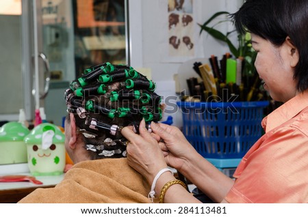 back view of the good looking Asian old woman making hair curl in the beauty salon