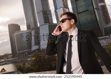 Businessman talking on the phone on the background of skyscrapers.