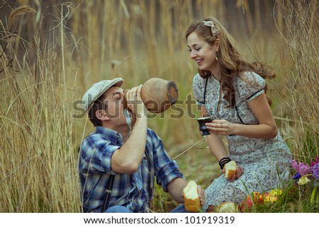 Image of young man and woman drink milk on field