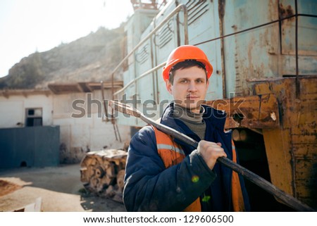 Portrait young man in a helmet worker standing with a hammer on the shoulder