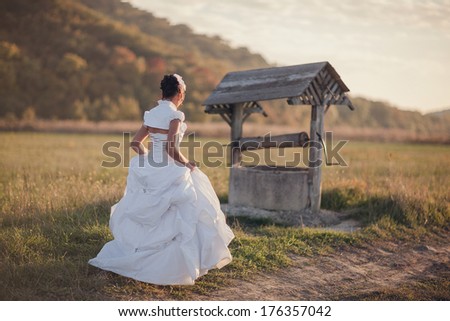 bride in a white wedding dress at the well water.  Wedding rustic theme.