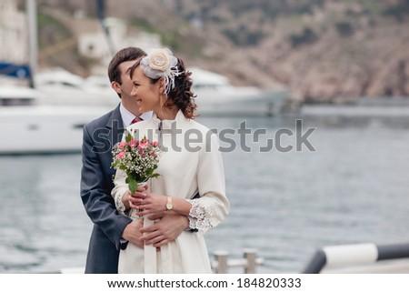 Young couple kissing on a date near the sea. Man in a suit and a woman in a white coat.