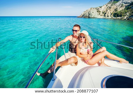 Romantic happy couple in love relaxing on a yacht at sea. Man and woman lying and hugging on a private boat cruising on the islands. Luxury holidays on the water.
