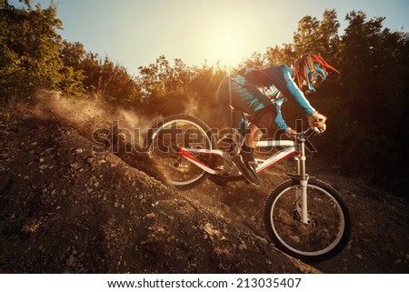 Man riding a mountain bike in downhill style at sunrise. Extreme sports on a bicycle.