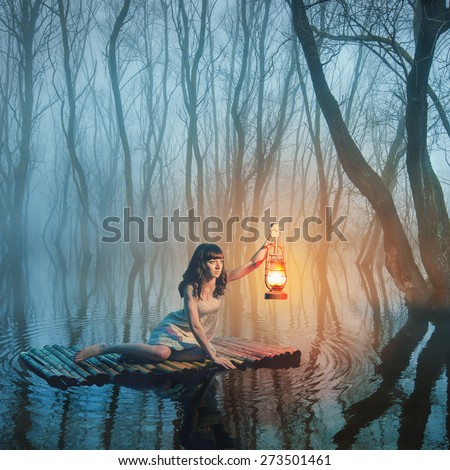 Woman with lantern floating on the lake in the misty forest in rustic white dress. Beautiful fairy tale.