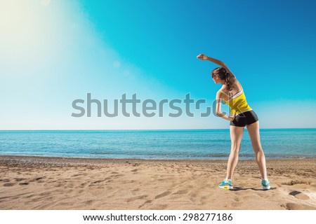 Sports training on the beach. Young sports woman stretching. Healthy lifestyle outdoors.