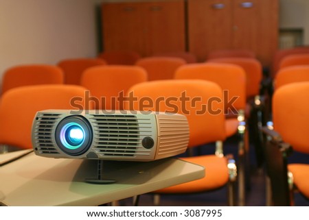 Projector on table ready for presentation with chairs on background