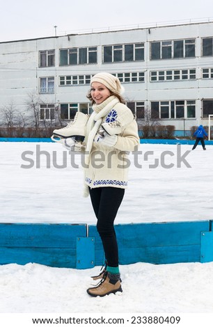 Smiling girl with fads in hands has come on domestic ice skating rink