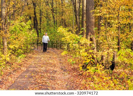 Walking through autumn forest - active elderly man walking on forest road