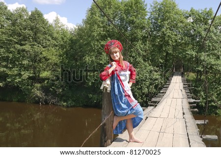 Woman in Russian Costume on a suspended bridge over the river