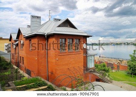 Cottage from a red brick in a landscape with the wide river