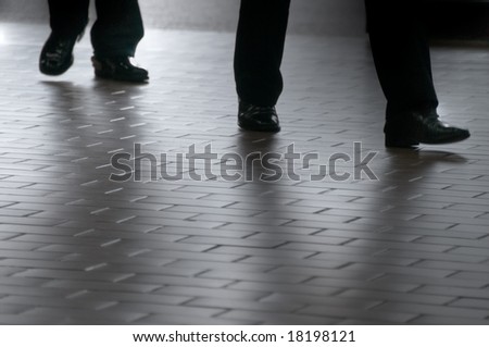 Two businessmen walking on a tiled floor