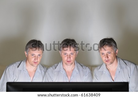 Three identical clones or triplets watching television or a computer screen together
