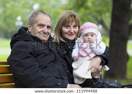Great-grandfather, grandmother and little baby girl on a bench in the park