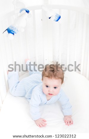 Cute baby playing in a white round crib