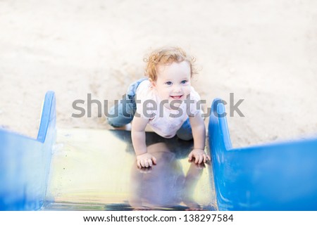 Laughing baby girl playing on a slide