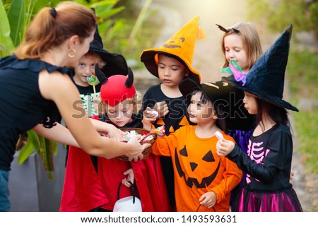 Kids trick or treat on Halloween night. Mixed race Asian and Caucasian children at decorated house door. Boy and girl in witch and vampire costume and hat with candy bucket and pumpkin lantern.  ストックフォト © 
