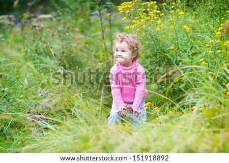 Funny laughing baby girl playing in a blooming garden on a nice autumn day