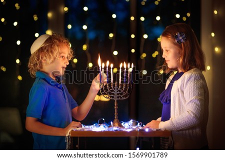 Kids celebrating Hanukkah. Jewish festival of lights. Children lighting candles on traditional menorah. Boy in kippah with dreidel and Sufganiyah doughnut. Israel holiday. ストックフォト © 
