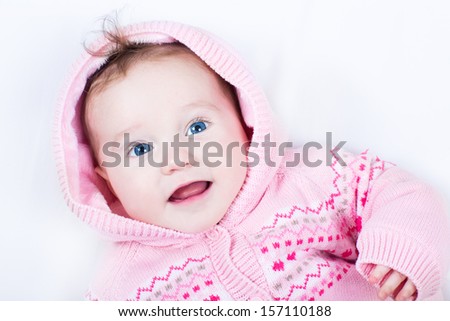 Happy smiling baby girl wearing a warm knitted jacket with heart ornament