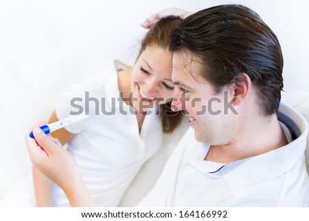 Excited young couple is laughing by looking at a positive pregnancy test