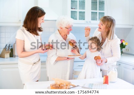 Four generations of women having fun together baking an apple pie in a beautiful white sunny kitchen