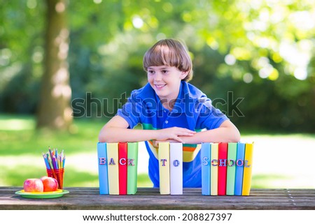 Happy laughing teenager student boy in the school garden reading books and having healthy snack, back to school concept