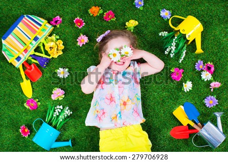 Kids gardening. Children with garden tools. Child with watering can and shovel. Little kid watering flowers. Girl relaxing on green backyard lawn in summer.