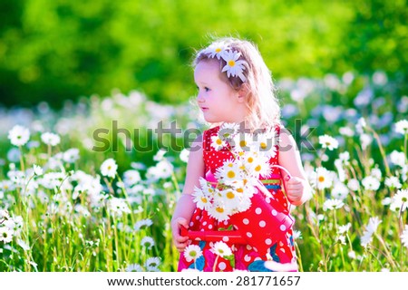 Kid gardening. Little girl with water can in a daisy flower field. Children playing in the backyard. Child working in the garden with daisies picking flowers. Outdoor summer fun for family with kids.