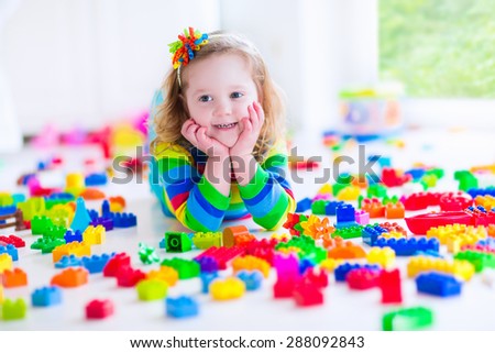 Preschooler child playing with colorful toy blocks. Kids play with educational toys at kindergarten or day care. Preschool children build tower with plastic block. Toddler kid in nursery.