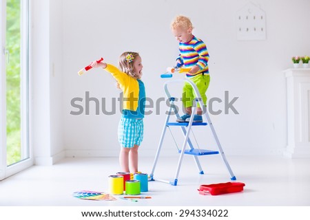 Family remodeling house. Home remodel and renovation. Kids painting walls with colorful brush and roller. Children paint wall. Choice of bright color on sample palette for child nursery or kid room.