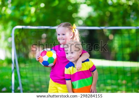 Two happy children playing European football outdoors in school yard. Kids play soccer. Active sport for preschool child. Ball game for young kid team. Boy and girl score a goal in football match.