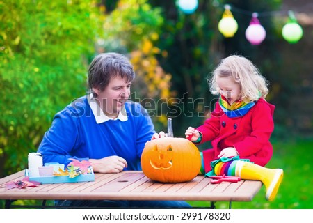 Family carving pumpkin at Halloween. Dressed up child trick or treating. Kids and parents trick or treat. Child in witch costume playing in autumn park. Toddler kid with jack-o-lantern.