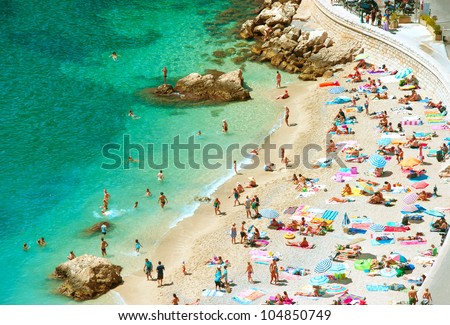 people on the sea beach with sunbeds and umbrellas. hot sunny summer day