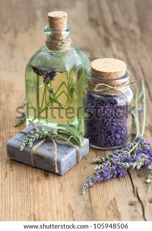 essential lavender oil, herbal soap and bath salt with fresh flowers on wooden background