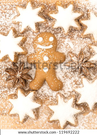 gingerbread man cookie, cinnamon stars and star anise on wooden background with sugar powder. christmas bakery