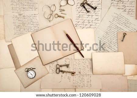 vintage accessories and open book over old letters and cards. nostalgic background